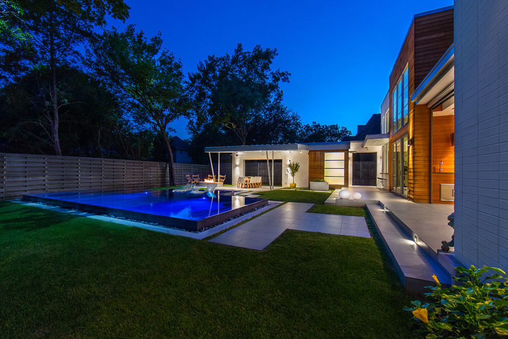 Photo of a large modern backyard rectangular pool in Dallas with a hot tub and tile.