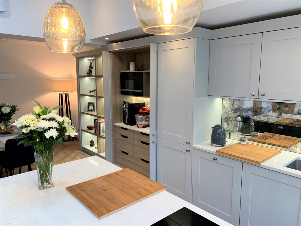 Photo of a large traditional single-wall open plan kitchen in Other with a single-bowl sink, shaker cabinets, medium wood cabinets, quartz worktops, glass sheet splashback, black appliances, vinyl flooring, an island and white worktops.