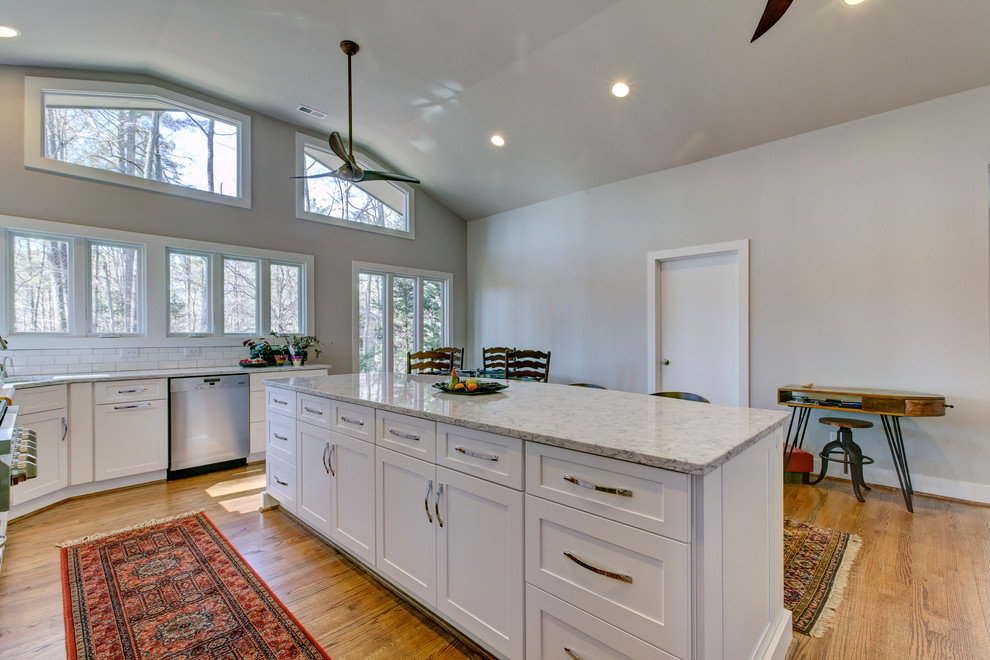Large transitional u-shaped medium tone wood floor eat-in kitchen photo in Raleigh with a single-bowl sink, shaker cabinets, white cabinets, quartz countertops, white backsplash, ceramic backsplash, stainless steel appliances and an island