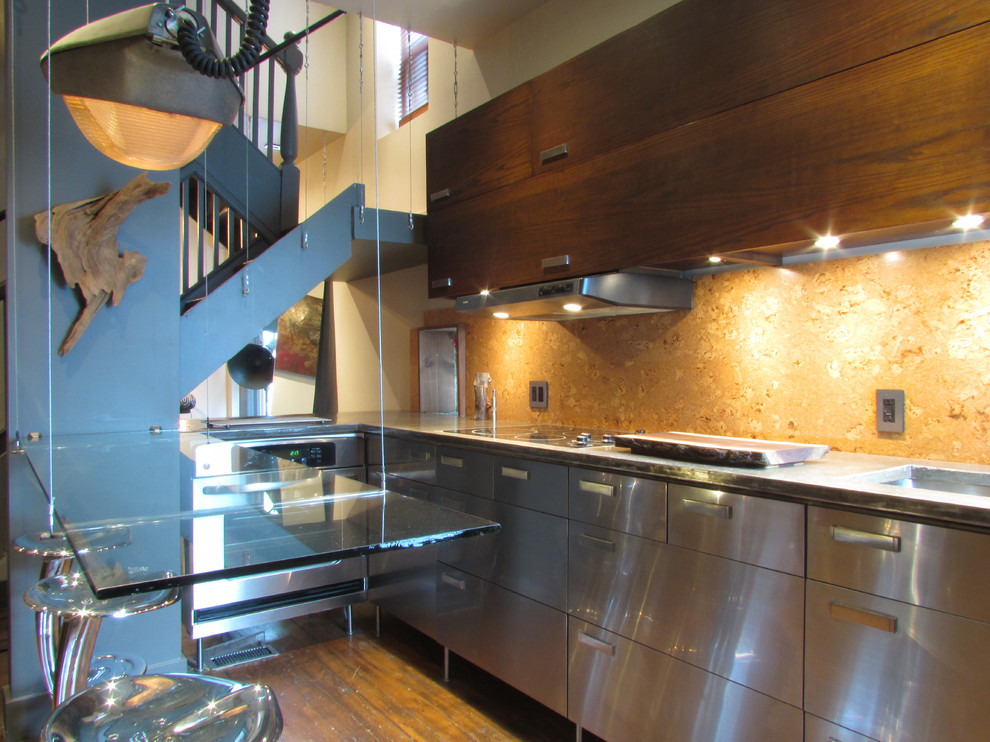 Industrial kitchen in Toronto with flat-panel cabinets, stainless steel cabinets and glass benchtops.