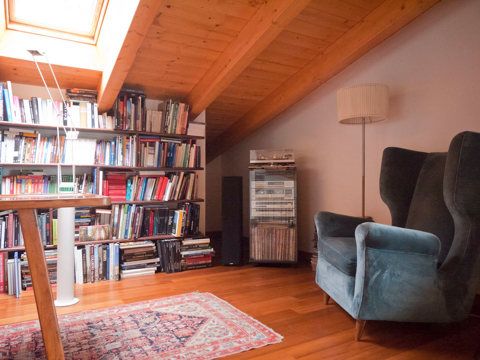 Photo of a large country loft-style living room in Milan with a library, white walls, medium hardwood floors and no tv.