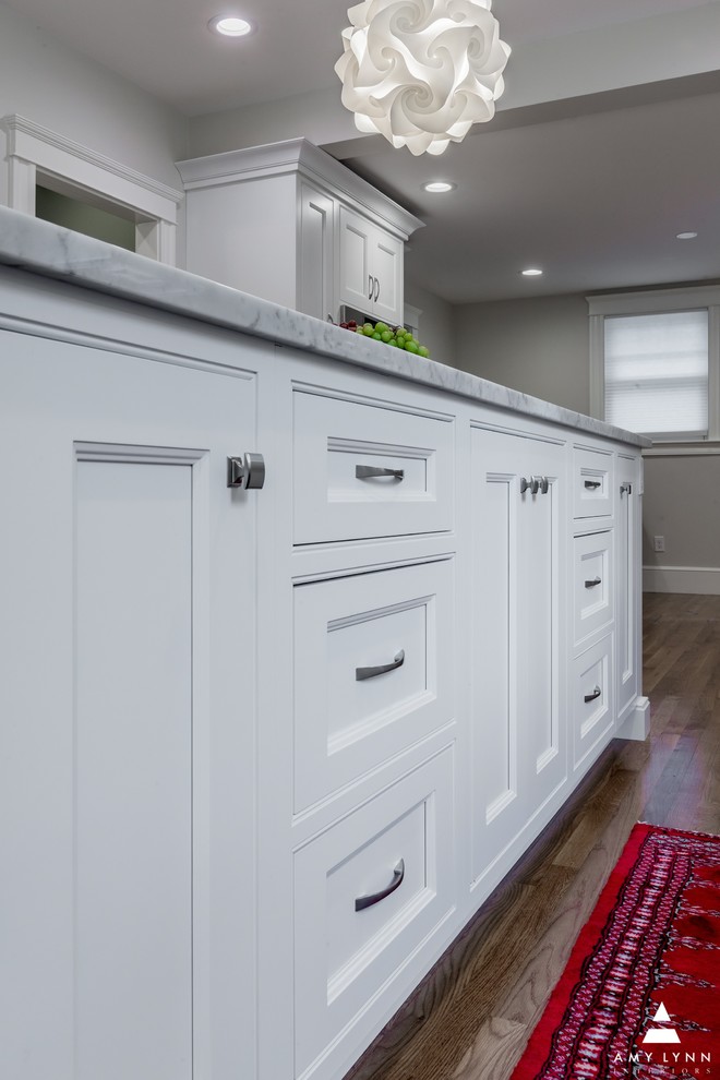 Eat-in kitchen - mid-sized transitional l-shaped medium tone wood floor and red floor eat-in kitchen idea in Boston with an undermount sink, beaded inset cabinets, white cabinets, marble countertops, gray backsplash, porcelain backsplash, paneled appliances, an island and yellow countertops