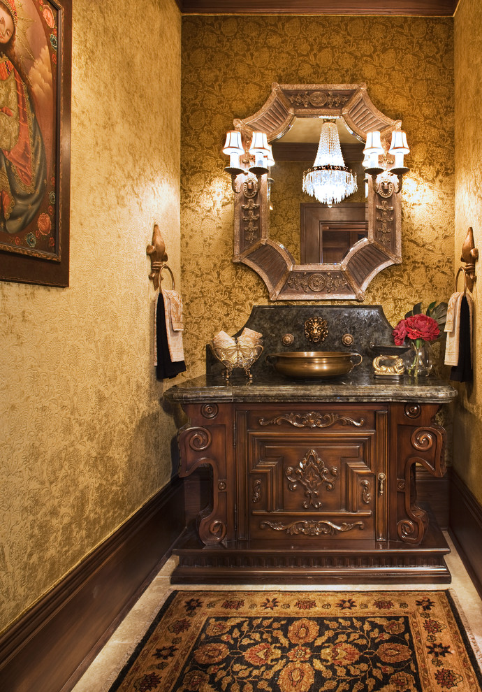This is an example of a mid-sized traditional powder room in Santa Barbara with furniture-like cabinets, a vessel sink, dark wood cabinets and limestone floors.