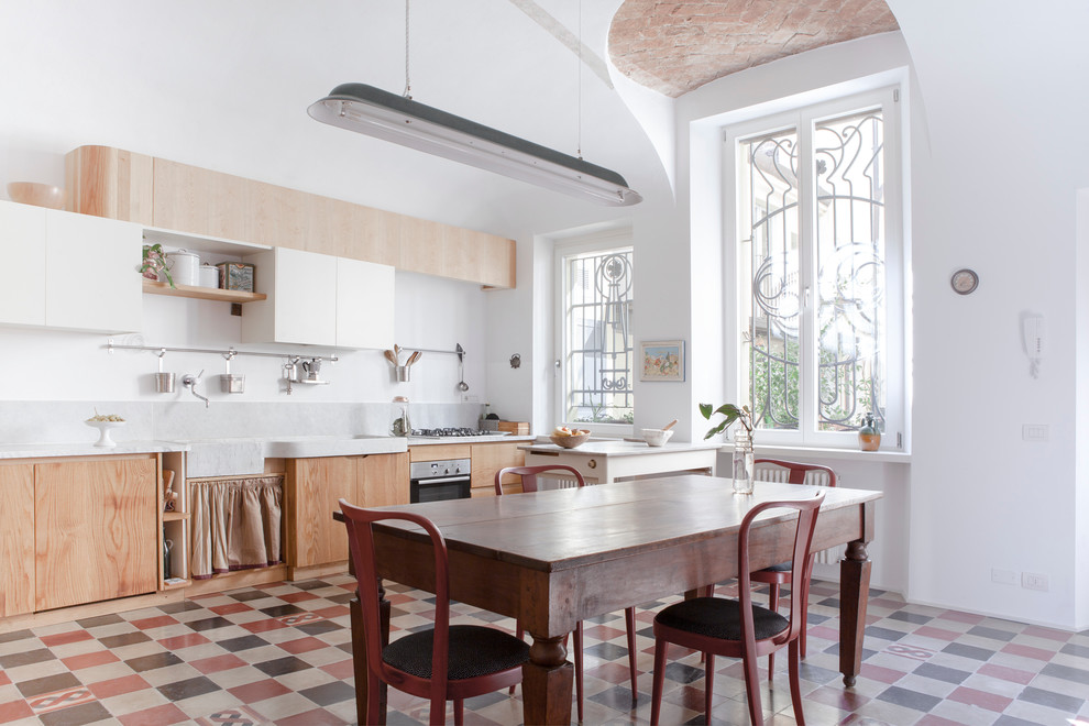 Photo of a large eclectic single-wall eat-in kitchen in Milan with flat-panel cabinets, light wood cabinets, grey splashback, stainless steel appliances, a peninsula and ceramic floors.