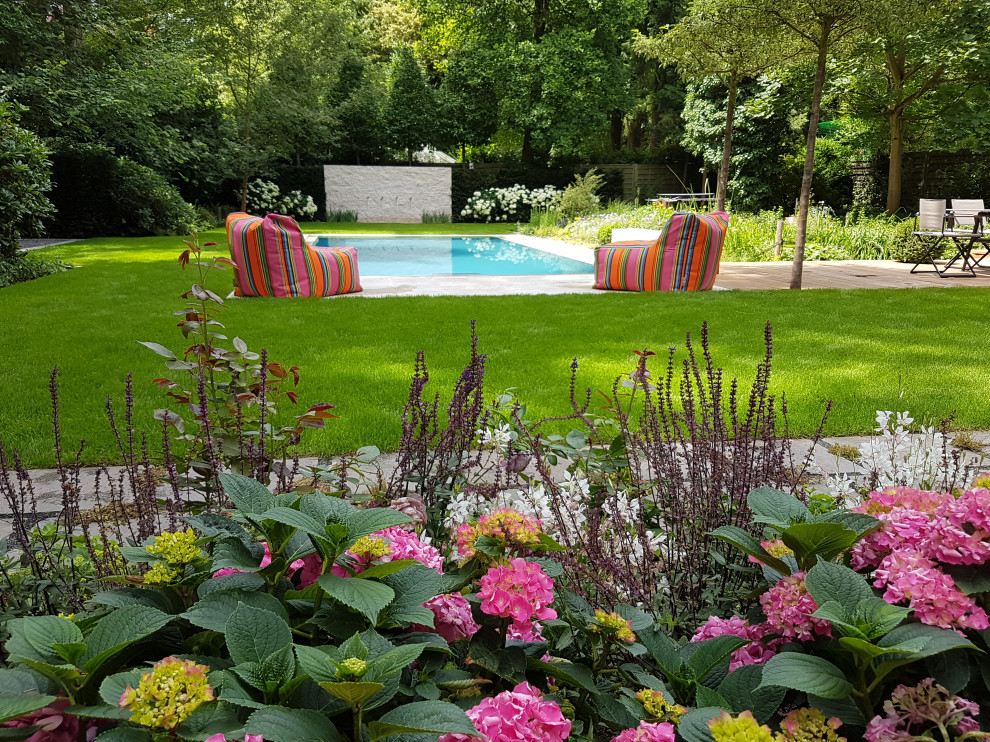This is an example of a large contemporary side yard rectangular pool in Frankfurt with a water slide and natural stone pavers.