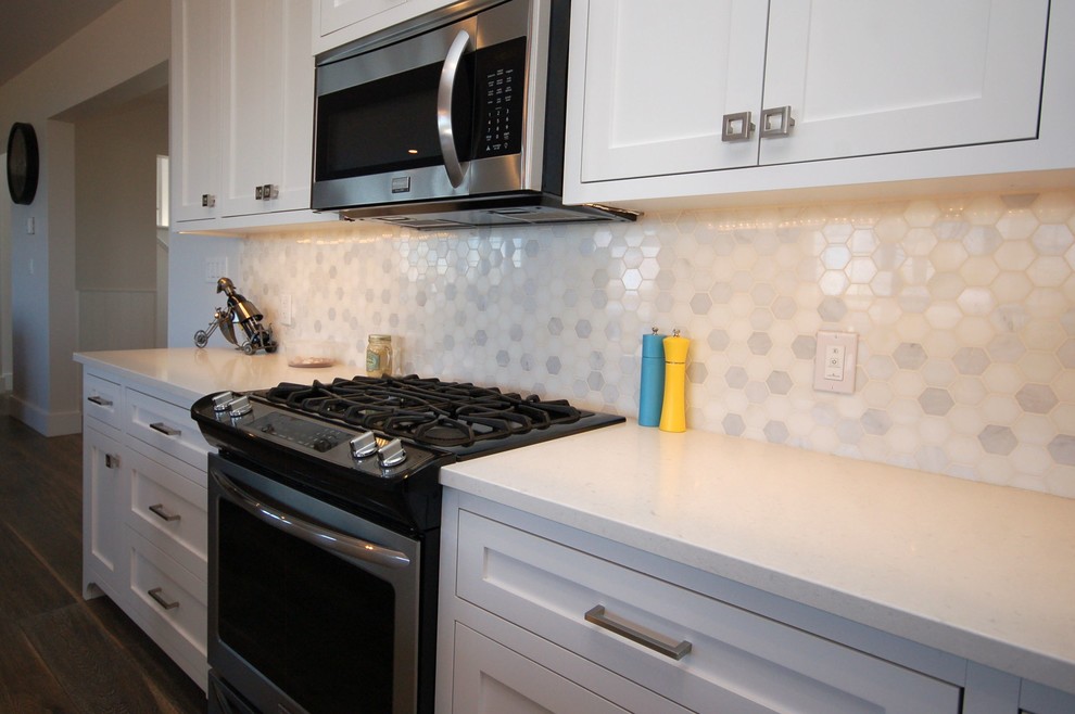 Example of a mid-sized transitional l-shaped dark wood floor and brown floor open concept kitchen design with a single-bowl sink, shaker cabinets, white cabinets, solid surface countertops, white backsplash, an island and stone tile backsplash