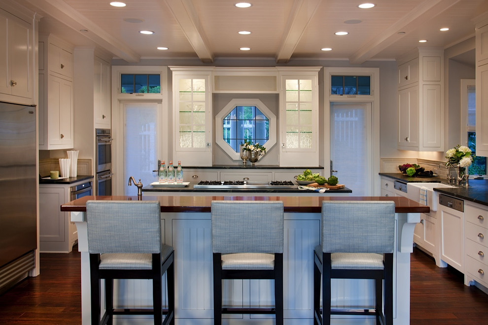 This is an example of a traditional kitchen in San Diego with white cabinets, white splashback, stainless steel appliances, dark hardwood floors and multiple islands.