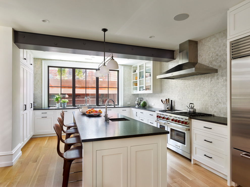 Transitional u-shaped kitchen in Philadelphia with an undermount sink, shaker cabinets, white cabinets, medium hardwood floors, with island, brown floor and black benchtop.