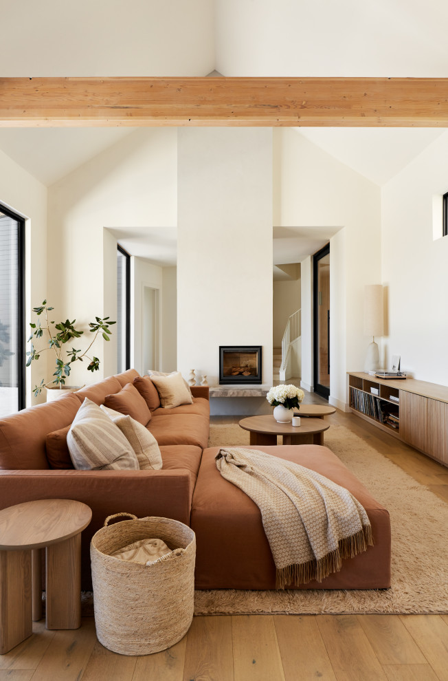 Diseño de salón abovedado escandinavo con paredes blancas, suelo de madera en tonos medios, todas las chimeneas, suelo marrón y vigas vistas