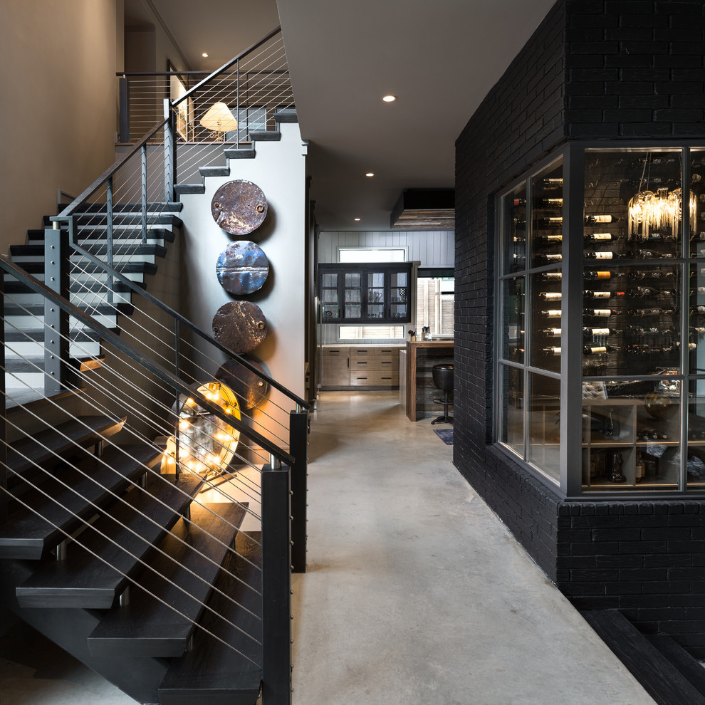 This is an example of a mid-sized contemporary wine cellar in Dallas with concrete floors and display racks.