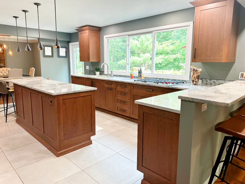 Eat-in kitchen - mid-sized transitional porcelain tile and gray floor eat-in kitchen idea with recessed-panel cabinets, medium tone wood cabinets, quartzite countertops, green backsplash, mosaic tile backsplash, stainless steel appliances and an island