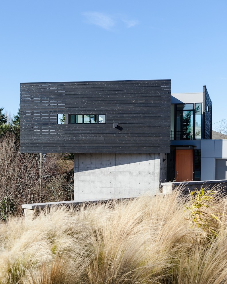 This is an example of a contemporary two-storey black exterior in Seattle with wood siding and a flat roof.