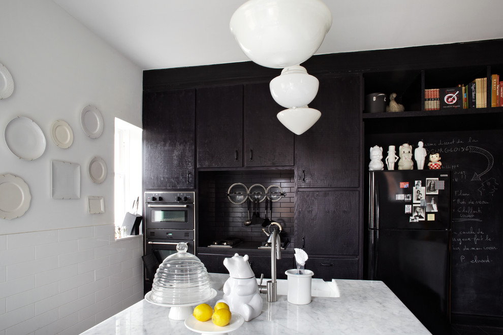 Inspiration for a contemporary kitchen in Toronto with a farmhouse sink, flat-panel cabinets, black splashback, subway tile splashback, black appliances and with island.