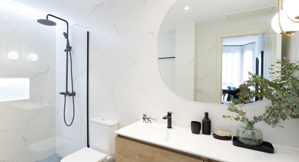 Modern inredning av ett mellanstort vit vitt en-suite badrum, med möbel-liknande, vita skåp, en kantlös dusch, en toalettstol med hel cisternkåpa, svart och vit kakel, keramikplattor, vita väggar, klinkergolv i keramik, ett integrerad handfat, bänkskiva i kvarts, grått golv och dusch med gångjärnsdörr