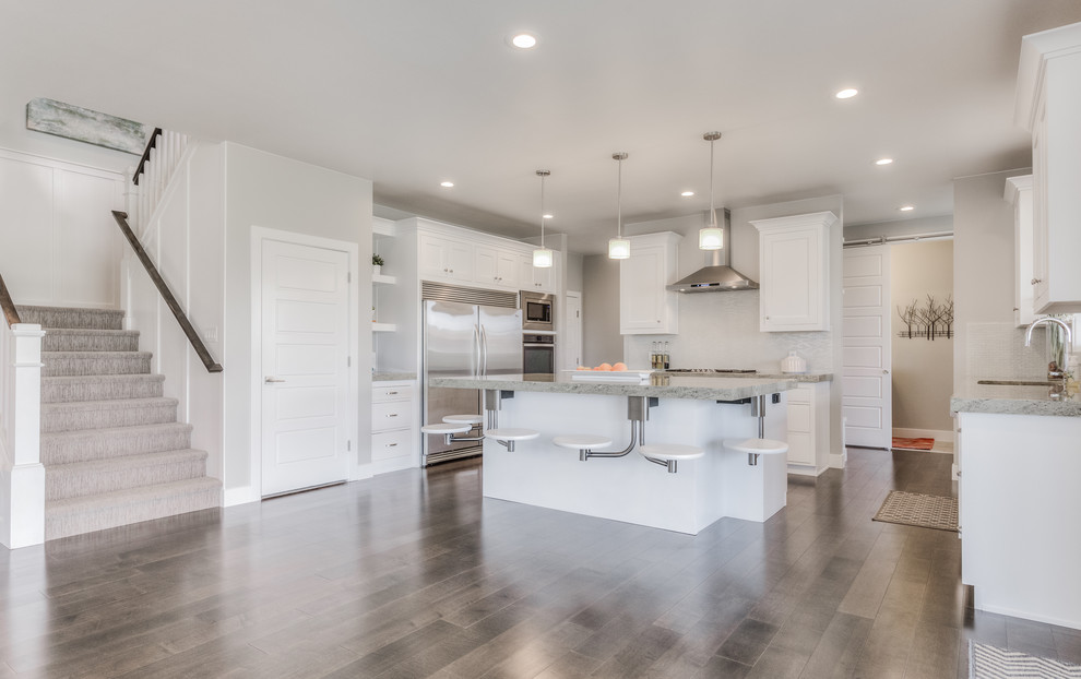 Mid-sized u-shaped light wood floor and brown floor open concept kitchen photo with a drop-in sink, beaded inset cabinets, white cabinets, granite countertops, stainless steel appliances and an island