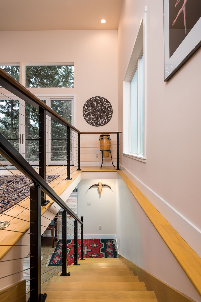 Large midcentury wood straight staircase in Portland with wood risers and cable railing.