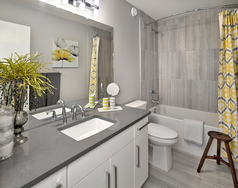 Large contemporary 3/4 bathroom in Edmonton with flat-panel cabinets, white cabinets, a shower/bathtub combo, gray tile, ceramic tile, grey walls, an undermount sink and engineered quartz benchtops.