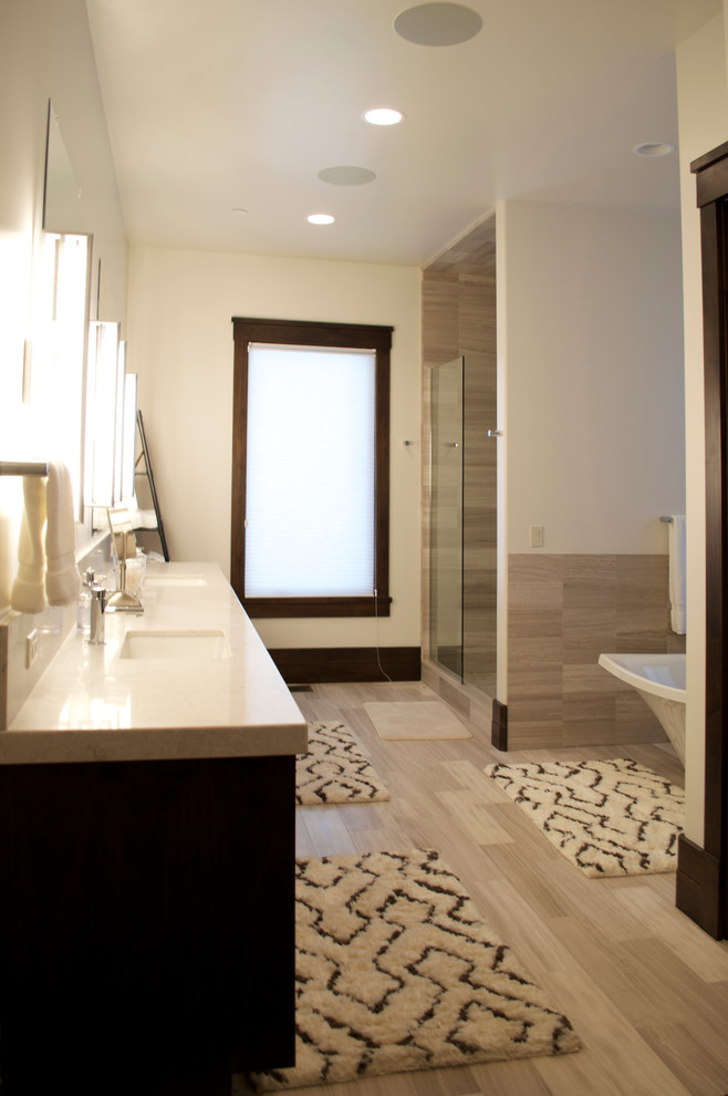 Design ideas for a mid-sized contemporary master bathroom in Salt Lake City with dark wood cabinets, gray tile, stone tile, white walls, an undermount sink, flat-panel cabinets, an undermount tub, an alcove shower, laminate floors, quartzite benchtops, brown floor, a hinged shower door and beige benchtops.