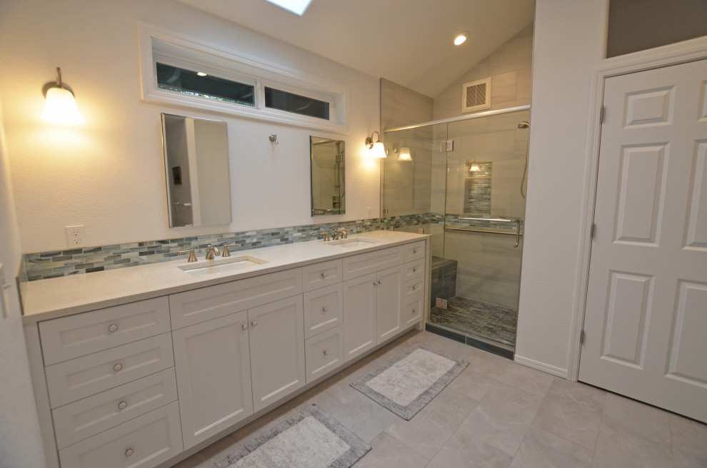 Medium sized traditional ensuite bathroom in Portland with shaker cabinets, white cabinets, an alcove shower, blue tiles, glass tiles, white walls, porcelain flooring, a submerged sink, quartz worktops, beige floors, a hinged door, beige worktops, a laundry area, double sinks, a built in vanity unit and a vaulted ceiling.