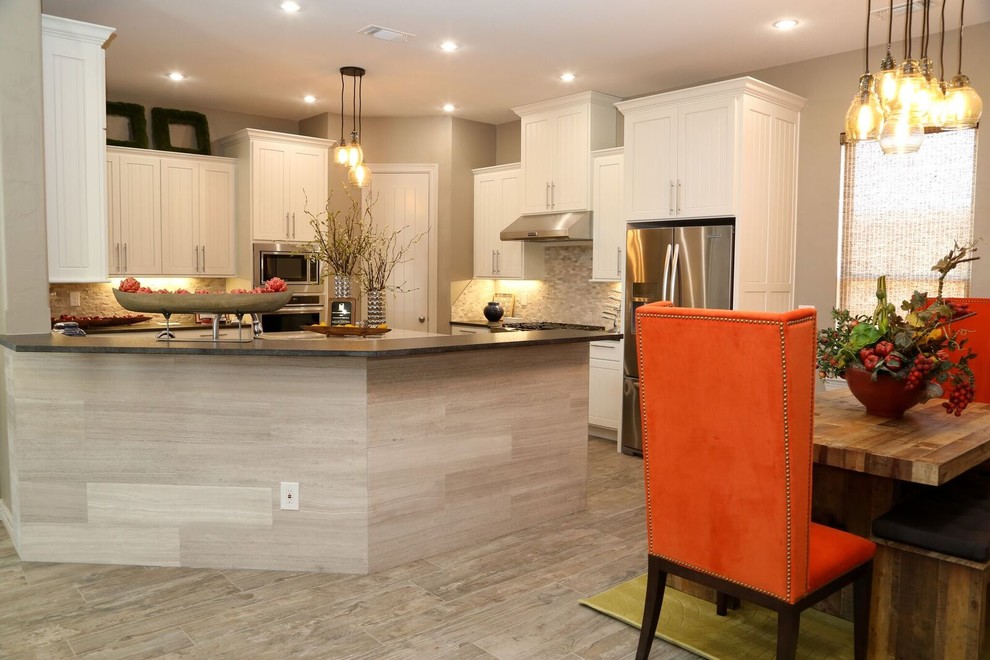 Inspiration for a small transitional u-shaped open plan kitchen in Orange County with louvered cabinets, white cabinets, solid surface benchtops, beige splashback, stone tile splashback, stainless steel appliances, multiple islands, an undermount sink and light hardwood floors.