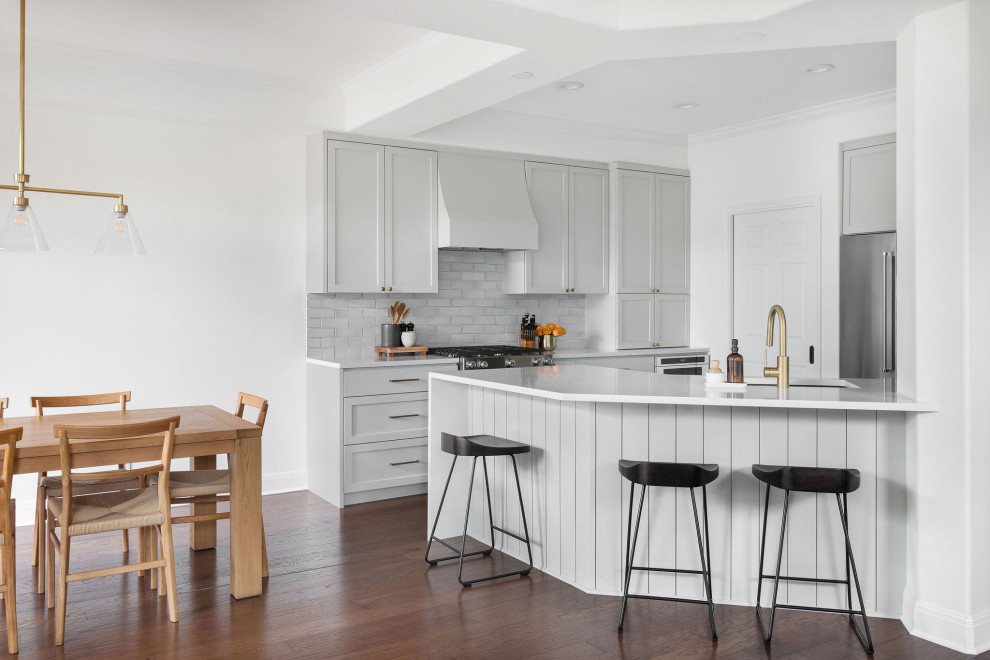 Example of a mid-sized transitional medium tone wood floor and brown floor kitchen design in Austin with an undermount sink, shaker cabinets, gray cabinets, quartz countertops, white backsplash, brick backsplash and white countertops