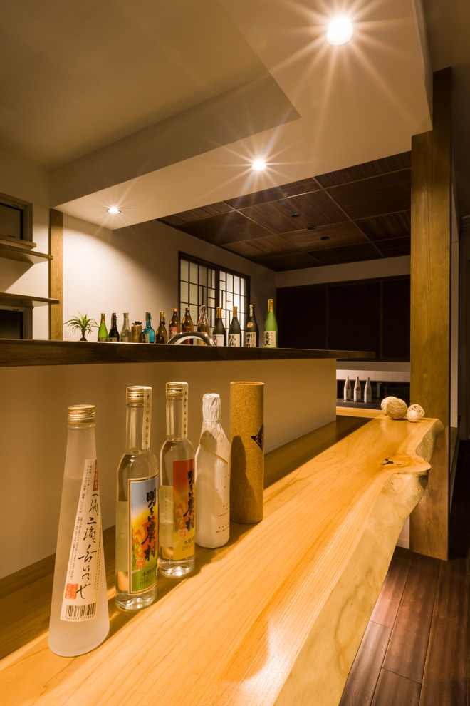 Photo of an asian home bar in Other with wood benchtops, dark hardwood floors, brown floor and beige benchtop.