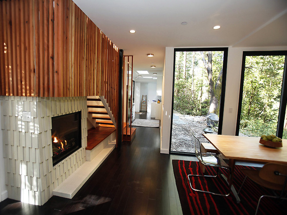 Inspiration for a modern dining room in San Francisco with white walls, dark hardwood floors and a standard fireplace.