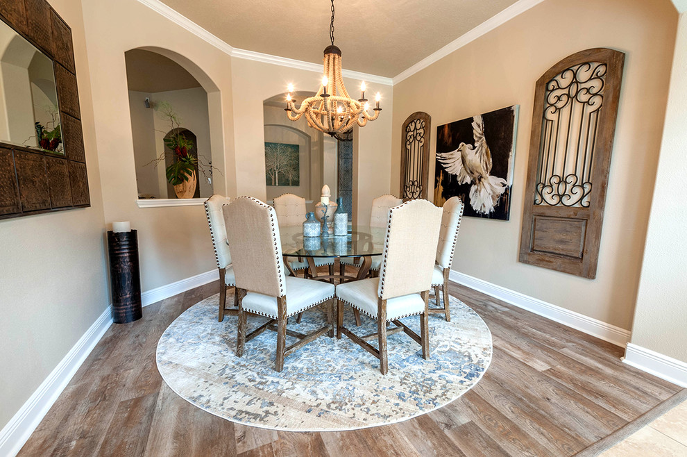 Photo of a mediterranean dining room in Houston with beige walls, laminate floors, no fireplace and brown floor.