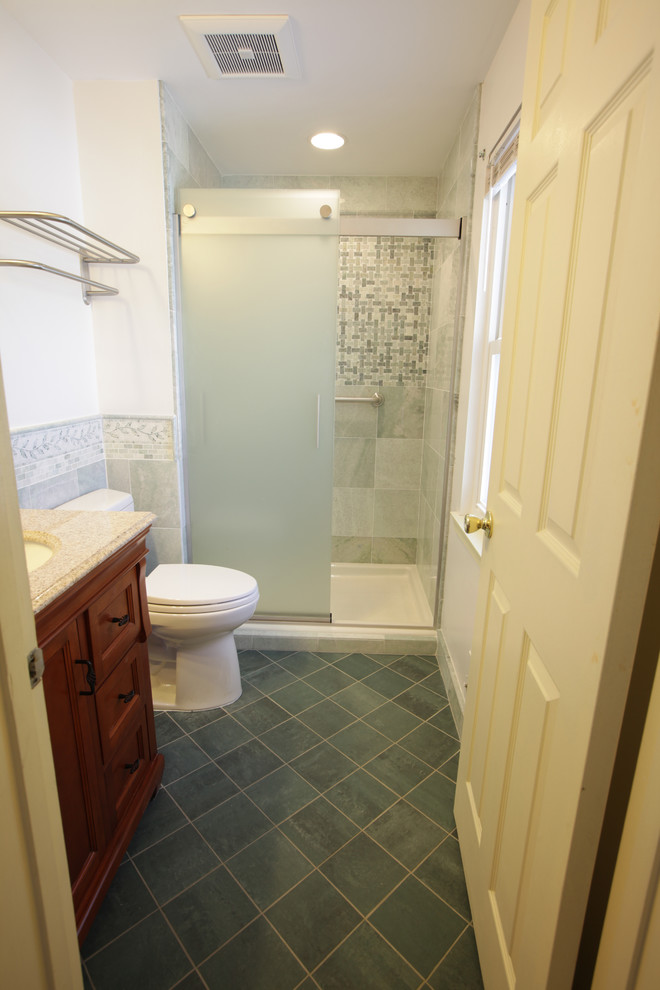 Photo of a small modern master bathroom in DC Metro with furniture-like cabinets, brown cabinets, an alcove shower, a two-piece toilet, green tile, marble, white walls, porcelain floors, an undermount sink, granite benchtops, green floor, a sliding shower screen and beige benchtops.