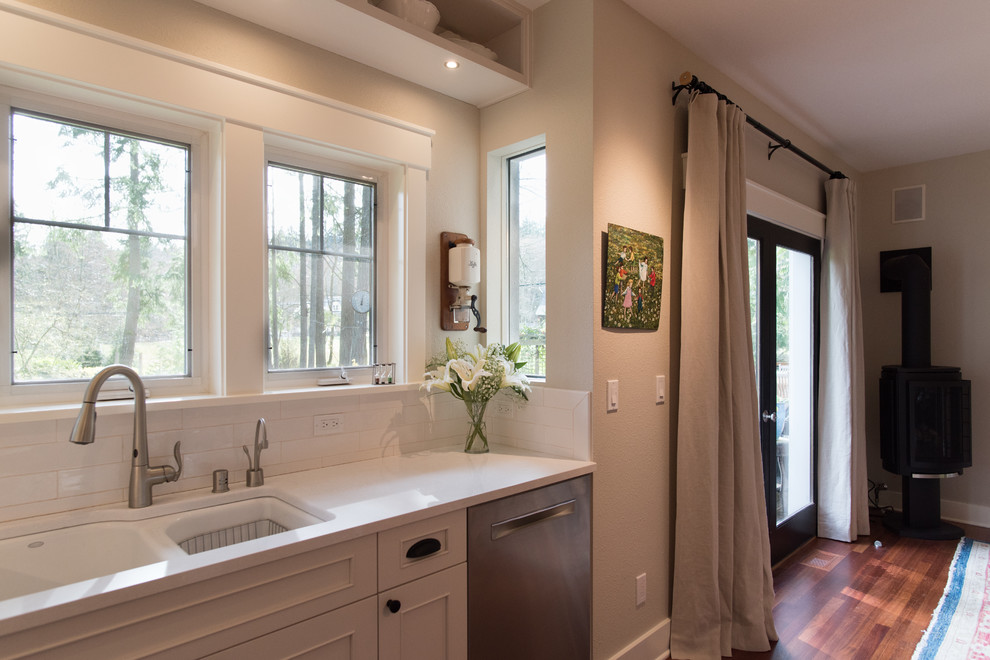 Inspiration for a mid-sized transitional l-shaped medium tone wood floor and brown floor eat-in kitchen remodel in Seattle with an undermount sink, recessed-panel cabinets, white cabinets, quartz countertops, white backsplash, ceramic backsplash, stainless steel appliances, an island and white countertops