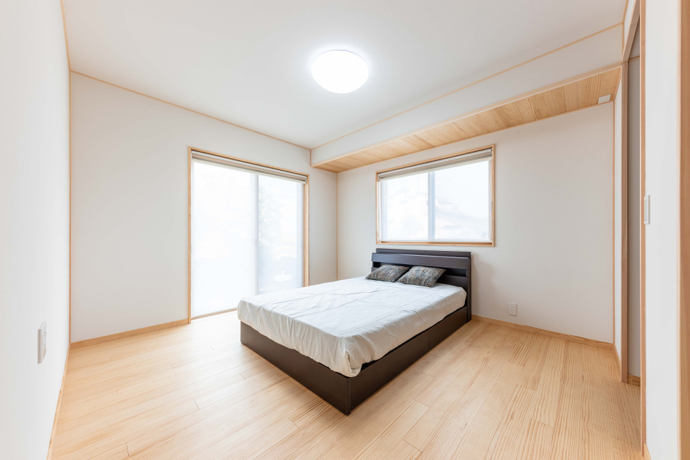 Ejemplo de dormitorio principal y blanco de estilo zen de tamaño medio con paredes blancas, suelo de madera en tonos medios, suelo marrón, papel pintado y papel pintado