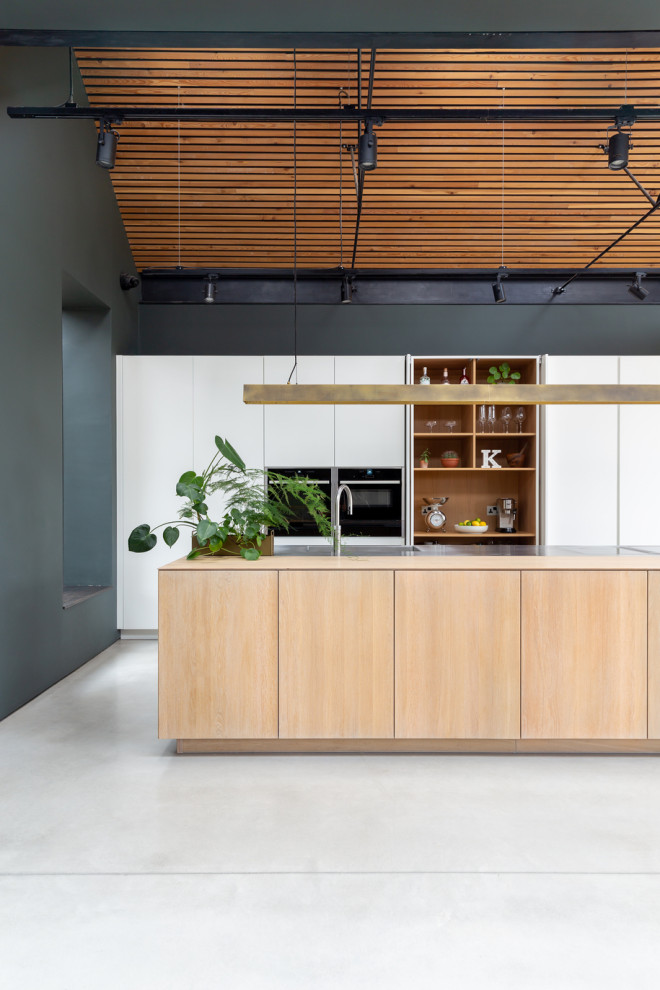 This is an example of an expansive scandinavian open plan kitchen in London with flat-panel cabinets, white cabinets, stainless steel benchtops, with island and multi-coloured benchtop.