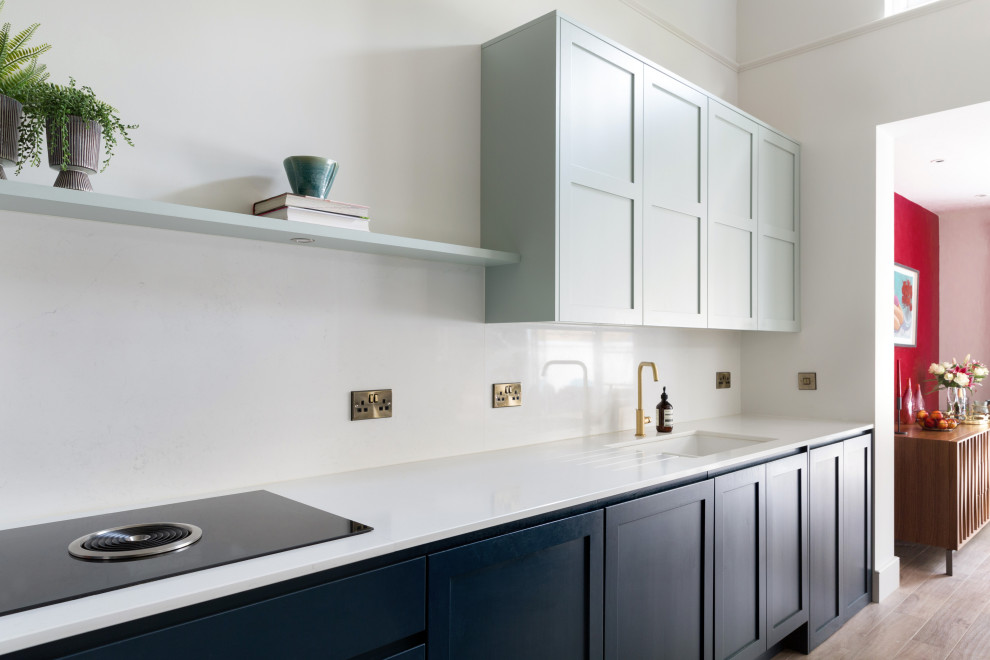 Inredning av ett klassiskt mellanstort vit vitt kök, med skåp i shakerstil, blå skåp, bänkskiva i koppar, vitt stänkskydd och en köksö
