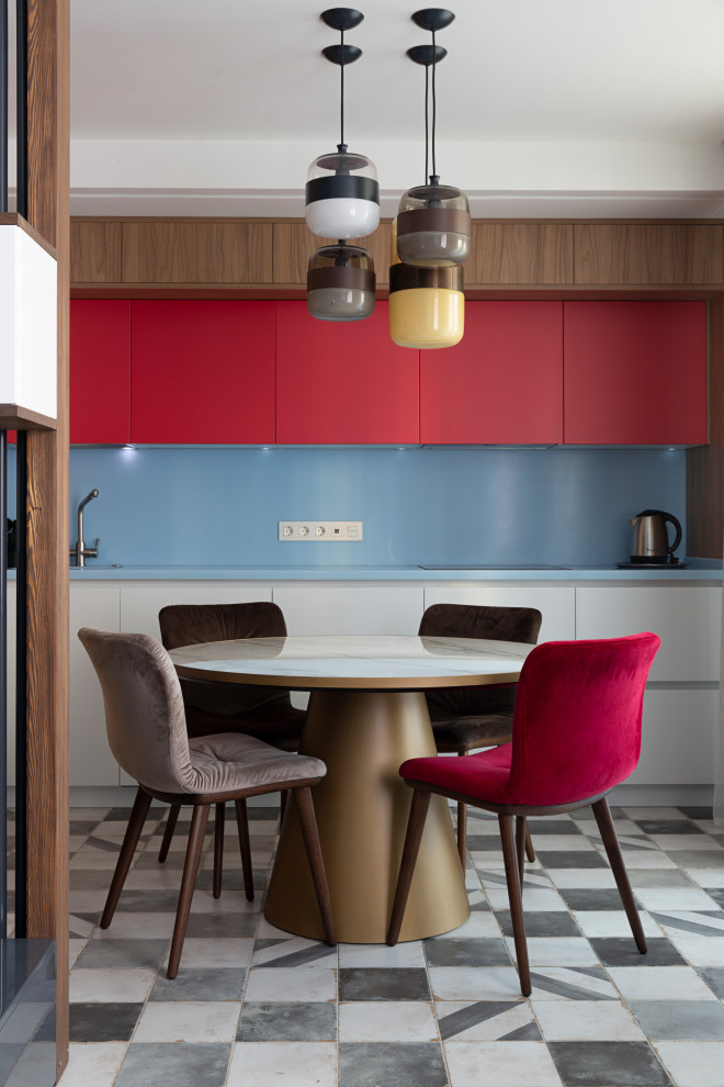 This is an example of a contemporary eat-in kitchen in Moscow with flat-panel cabinets, red cabinets, blue splashback, no island, multi-coloured floor and blue benchtop.