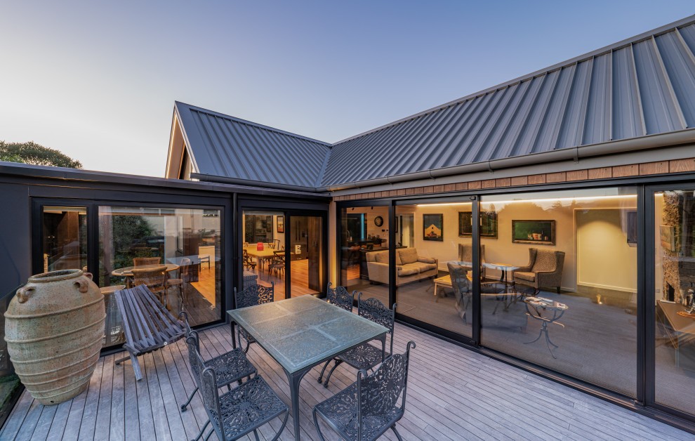 Example of a mid-sized transitional side yard second story mixed material railing deck design with a roof extension