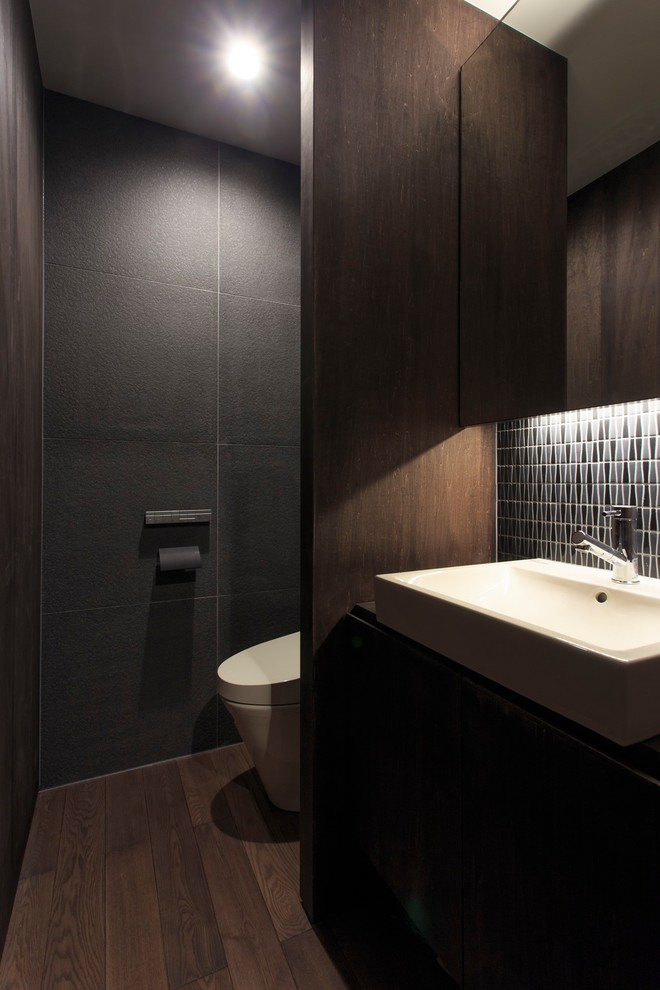 Design ideas for an asian powder room in Other with flat-panel cabinets, dark wood cabinets, grey walls, dark hardwood floors, a vessel sink and brown floor.