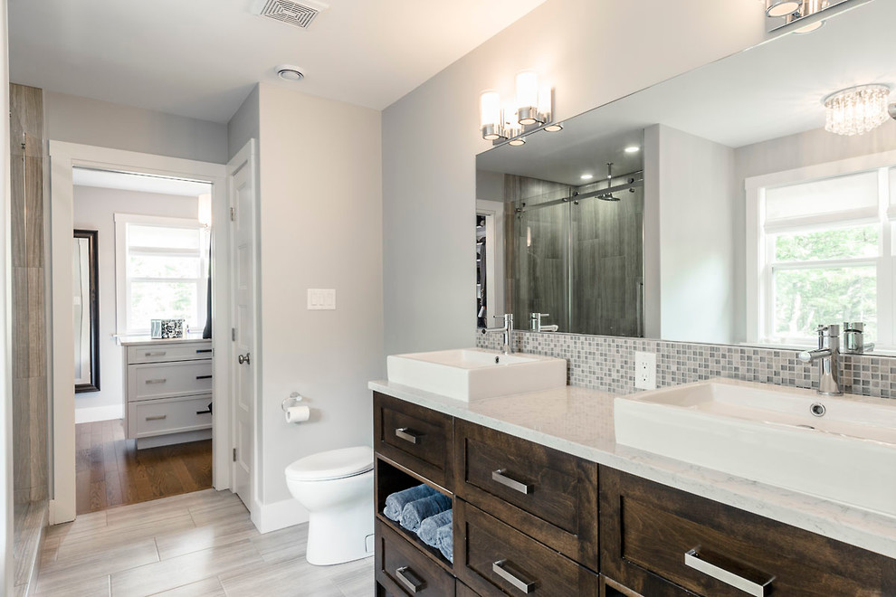 Inspiration for a huge transitional master gray tile and glass tile ceramic tile freestanding bathtub remodel with a vessel sink, dark wood cabinets, marble countertops and gray walls