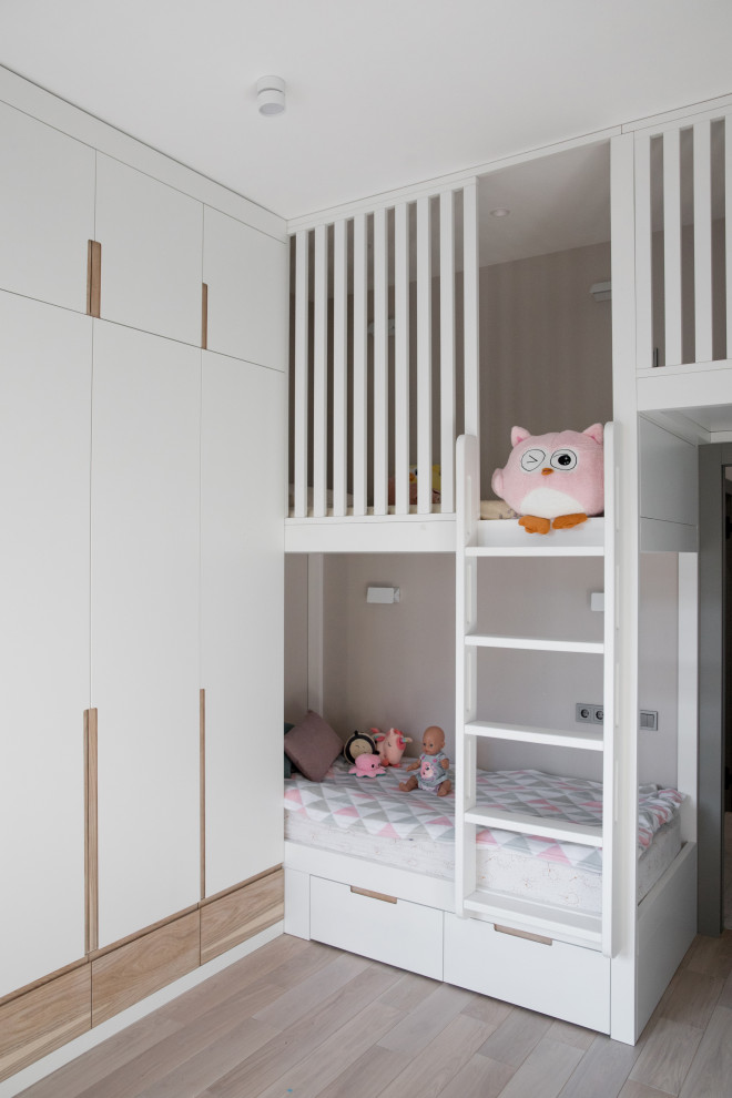 This is an example of a medium sized scandi children’s room for girls in Moscow with grey walls, light hardwood flooring and beige floors.