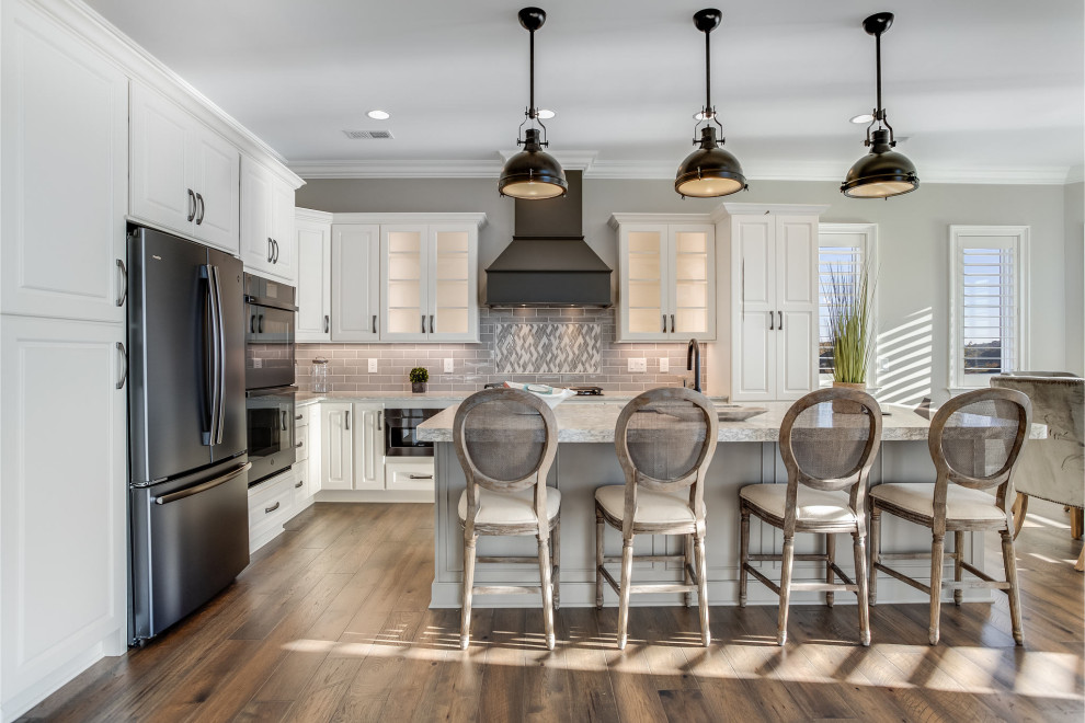 Open concept kitchen - large transitional l-shaped open concept kitchen idea with an undermount sink, raised-panel cabinets, white cabinets, quartz countertops, gray backsplash, subway tile backsplash, stainless steel appliances, an island and white countertops