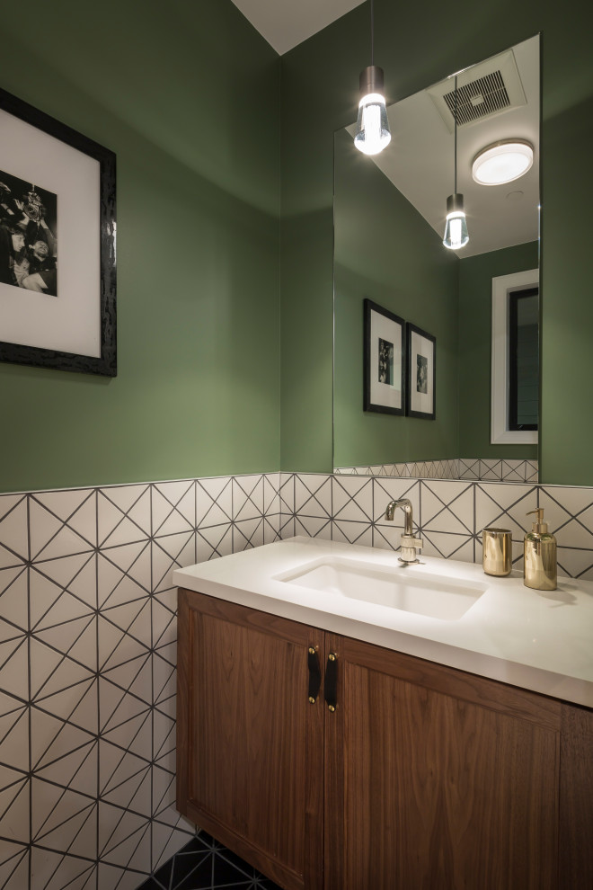 Photo of a small transitional powder room in San Francisco with shaker cabinets, medium wood cabinets, a wall-mount toilet, white tile, ceramic tile, green walls, ceramic floors, an undermount sink, engineered quartz benchtops, black floor, white benchtops and a freestanding vanity.