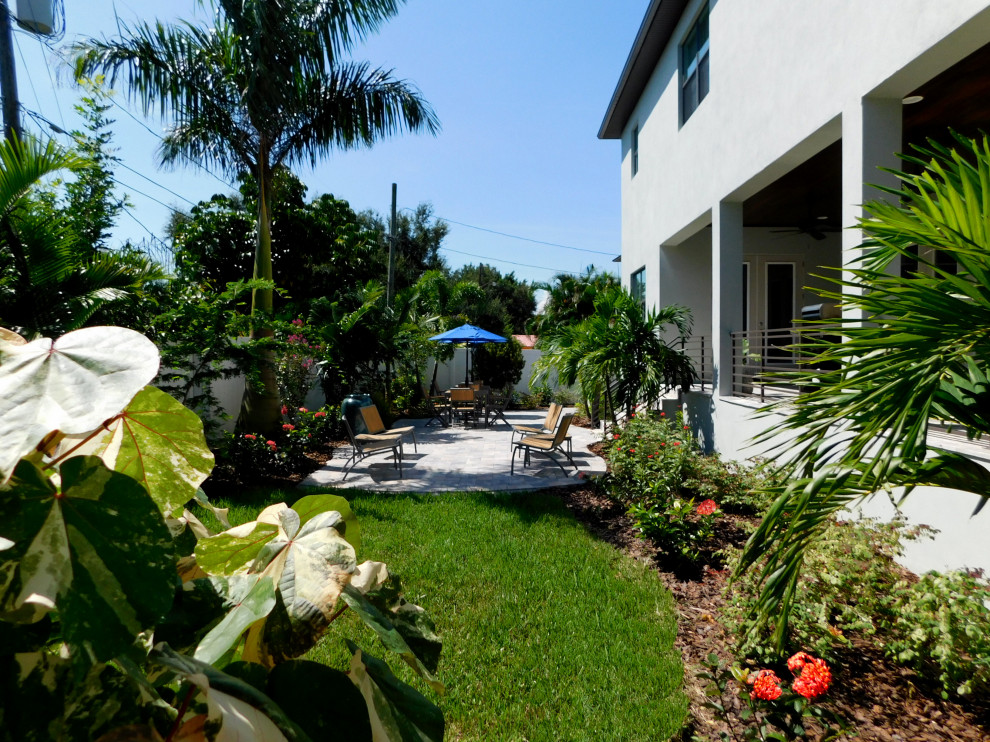 Mid-sized tropical backyard full sun formal garden in Tampa with with privacy feature and concrete pavers for summer.