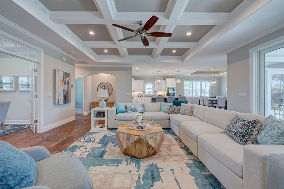 Medium sized nautical open plan living room in Wilmington with beige walls, medium hardwood flooring, a standard fireplace, a wooden fireplace surround, a wall mounted tv, brown floors and a coffered ceiling.