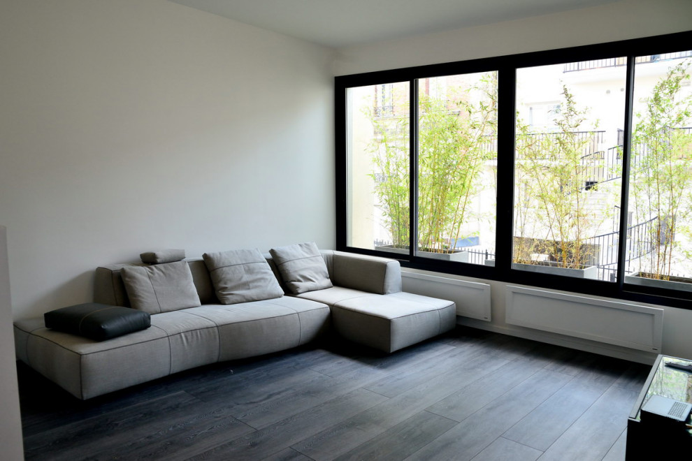 Foto de sala de estar abierta y abovedada actual sin chimenea con paredes blancas, suelo laminado, televisor independiente y suelo gris