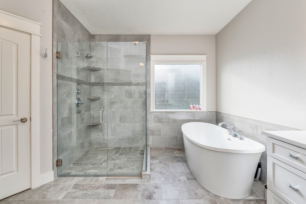 Mid-sized transitional master gray tile and porcelain tile porcelain tile and gray floor freestanding bathtub photo in Boise with shaker cabinets, white cabinets, a two-piece toilet, gray walls, an undermount sink, quartz countertops and a hinged shower door