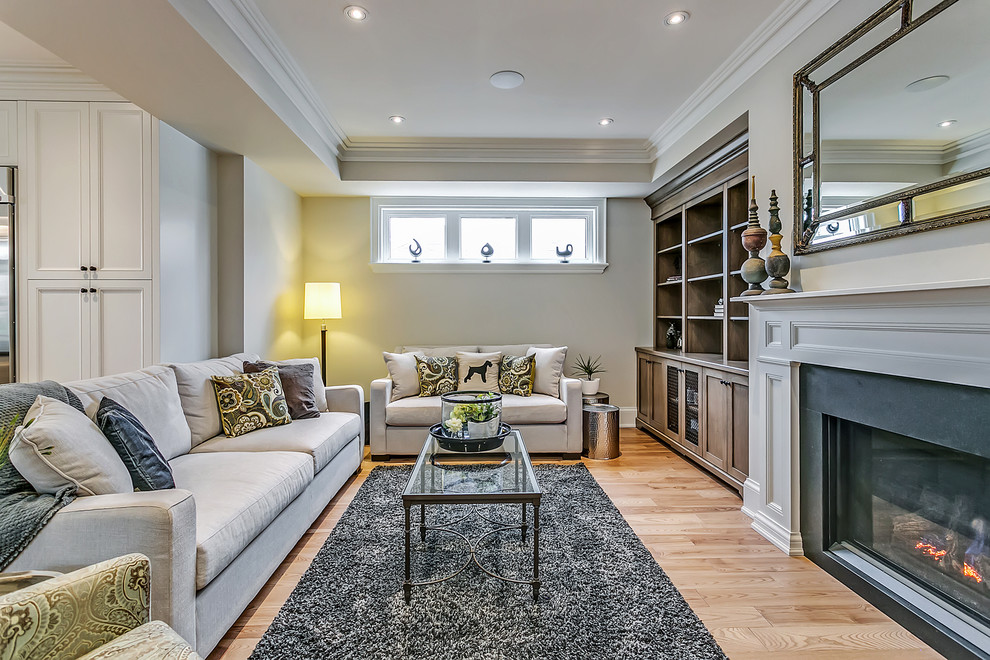 This is an example of a mid-sized traditional formal enclosed living room in Toronto with grey walls, light hardwood floors, a standard fireplace, no tv and a metal fireplace surround.