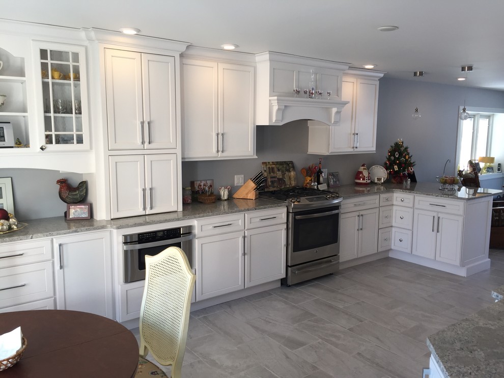 Large transitional l-shaped porcelain tile and gray floor eat-in kitchen photo with an undermount sink, shaker cabinets, white cabinets, granite countertops, stainless steel appliances and no island