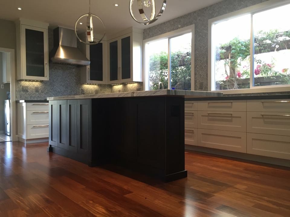 Inspiration for a mid-sized transitional u-shaped medium tone wood floor enclosed kitchen remodel in Seattle with a farmhouse sink, recessed-panel cabinets, white cabinets, marble countertops, gray backsplash, stone tile backsplash, stainless steel appliances and an island
