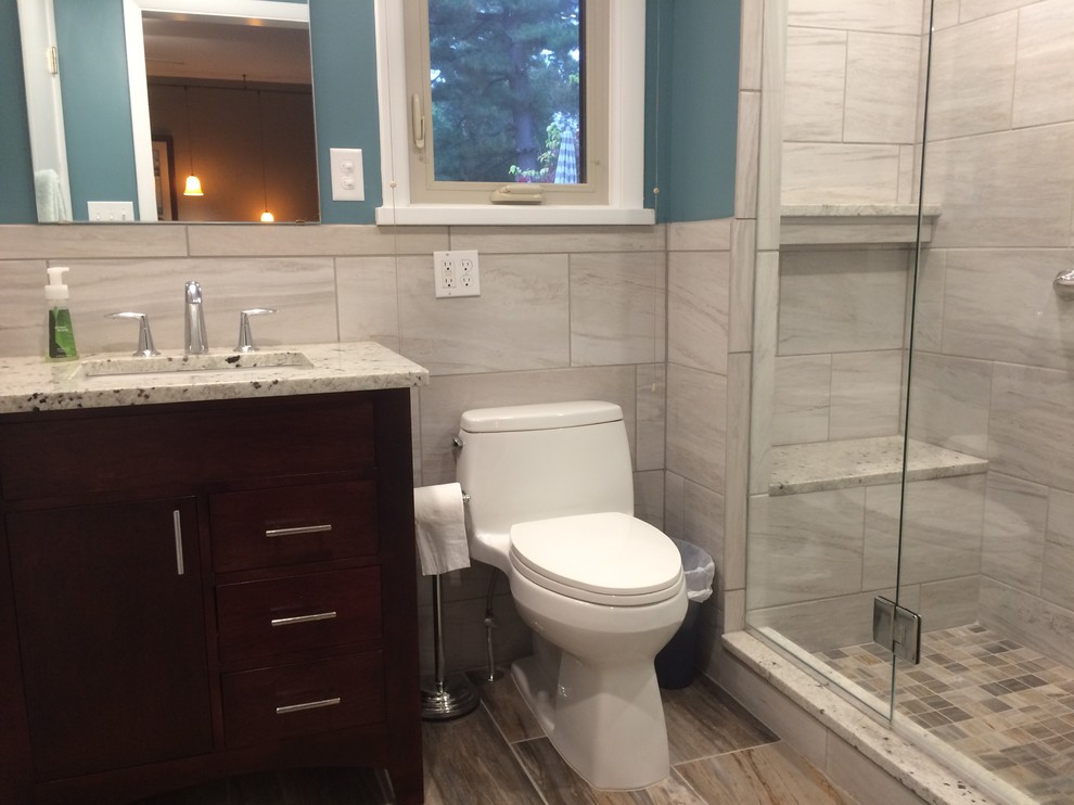 This is an example of a mid-sized traditional 3/4 bathroom in St Louis with flat-panel cabinets, dark wood cabinets, an alcove shower, a one-piece toilet, gray tile, porcelain tile, blue walls, porcelain floors, an undermount sink, granite benchtops, brown floor and a sliding shower screen.