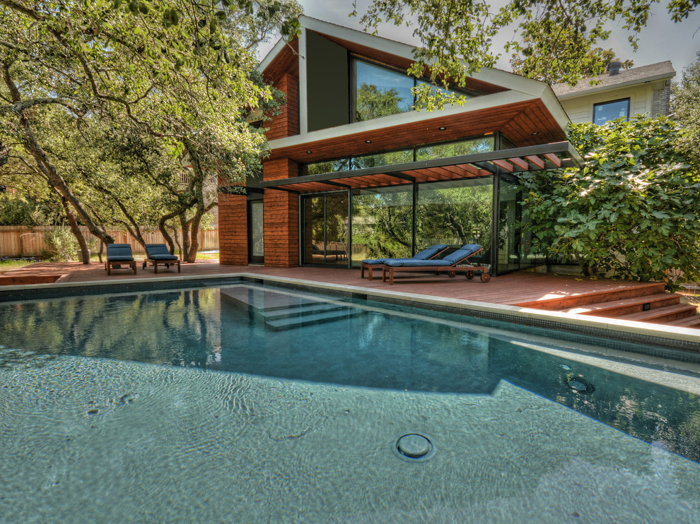 This is an example of a large contemporary backyard rectangular lap pool in Austin with decking.