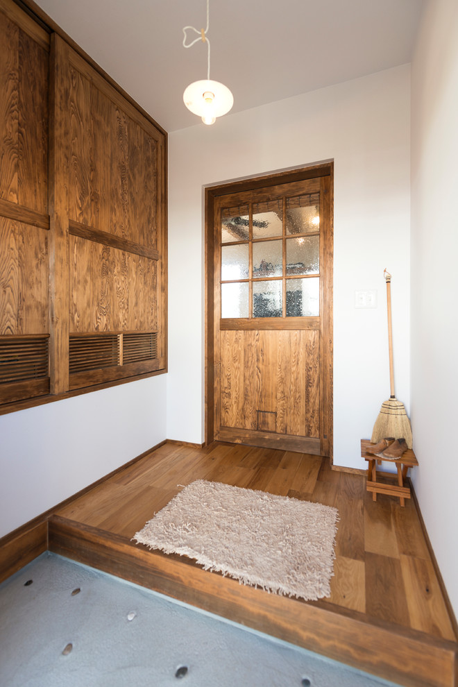 This is an example of an asian entryway in Other with white walls, concrete floors and grey floor.
